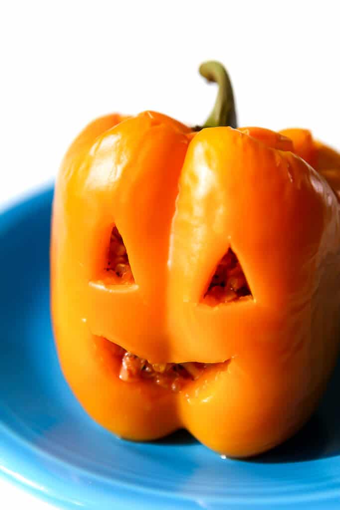 A vegan stuffed pepper carved to look like a jack-o-lantern.