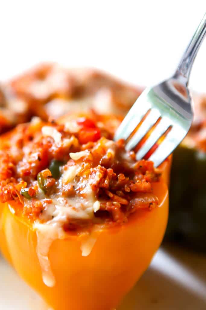 A vegan yellow stuffed pepper with a fork in it about to take out some filling.