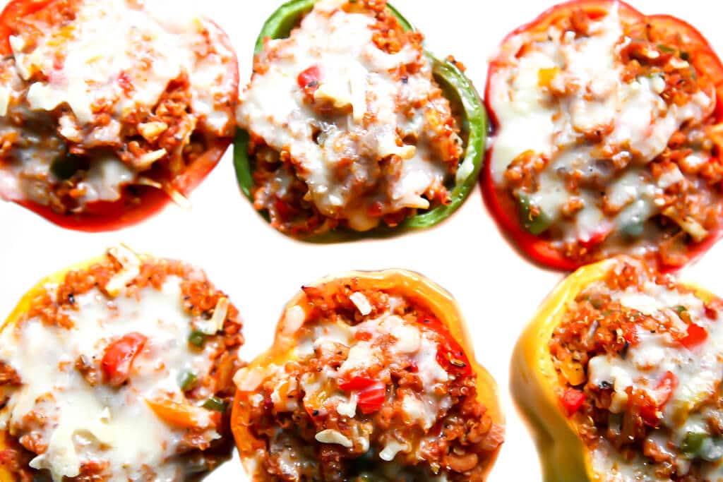 Six vegan stuffed peppers with red, yellow, orange and green bell peppers.