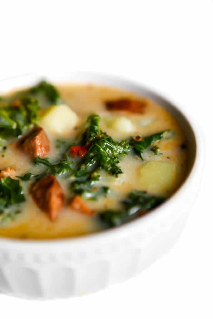 A bowl of vegan sausage soup with potatoes and kale.
