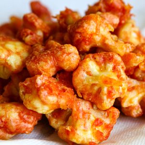 A close-up of vegan breaded and deep-fried cauliflower nuggets on a paper towel.