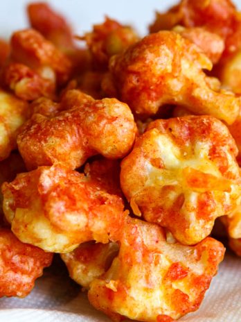 A close-up of vegan breaded and deep-fried cauliflower nuggets on a paper towel.
