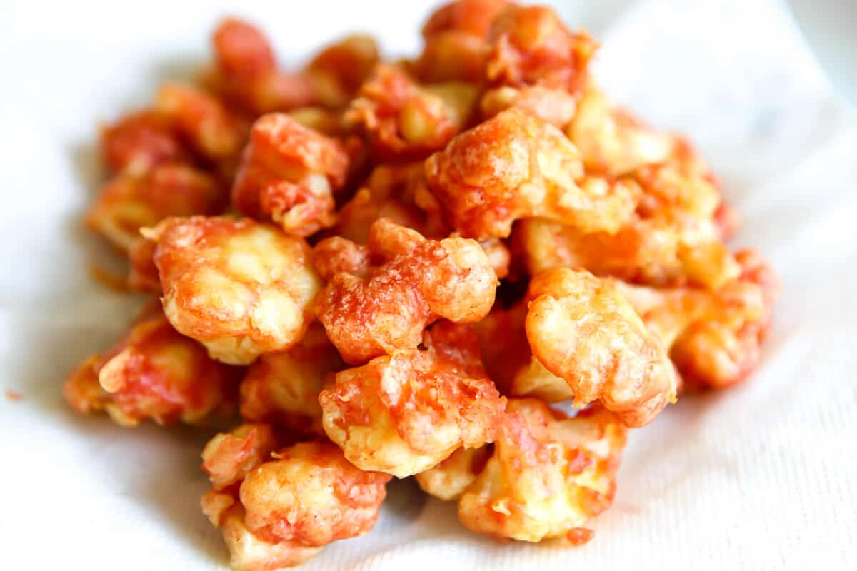 A plate of spicy fried cauliflower on a paper towel after frying.