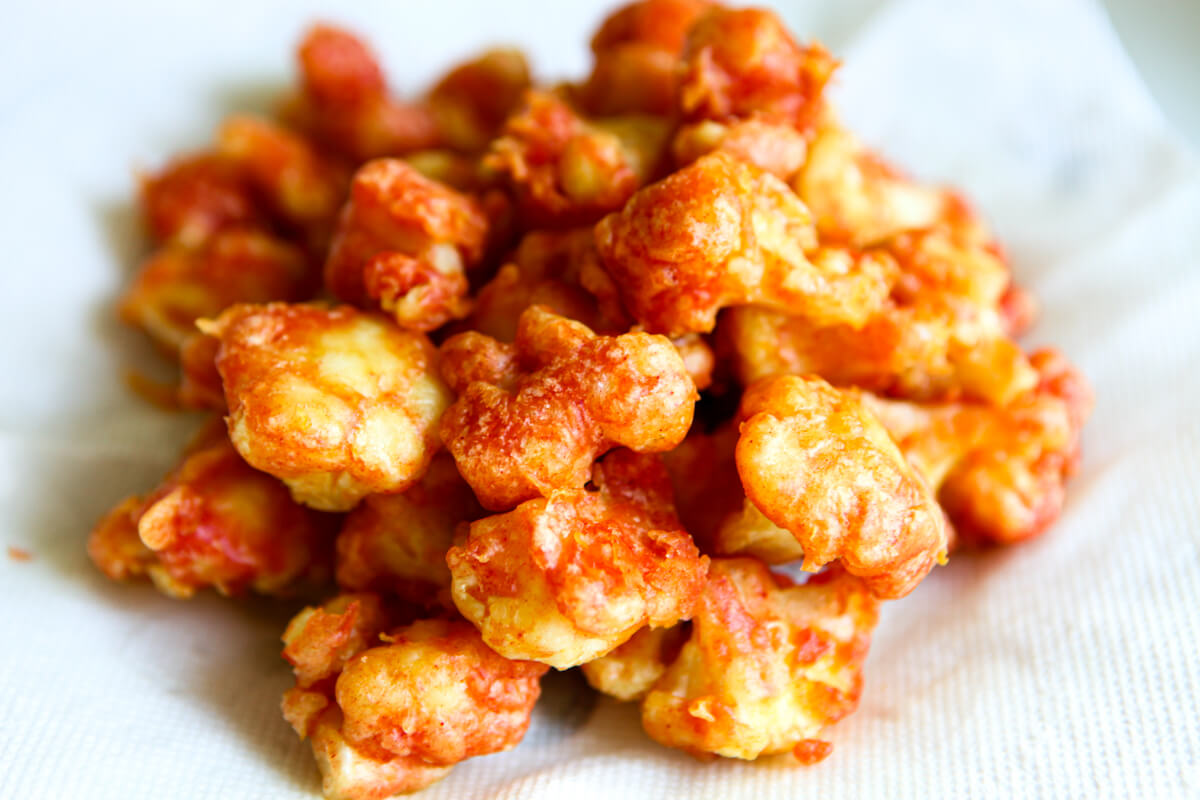 A plate of spicy fried cauliflower on a paper towel after frying.