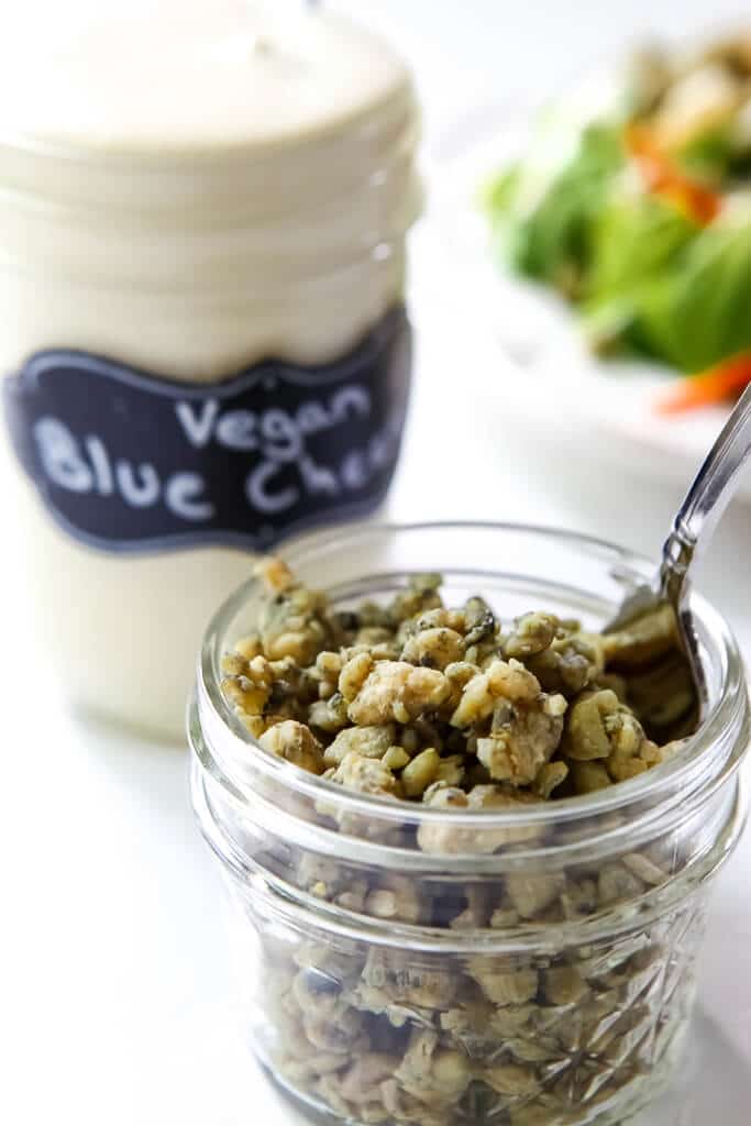 A jar of crumbly vegan blue cheese with another jar of vegan blue cheese dressing behind it.