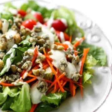 A salad with vegan blue cheese dressing and vegan blue cheese crumbles on top.