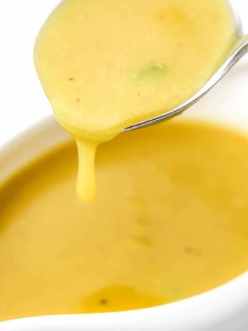 A close up of a scoop of vegan gravy in a gravy spoon.