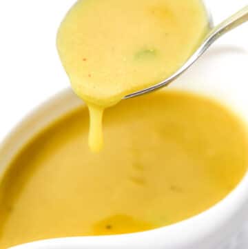 A close up of a scoop of vegan gravy in a gravy spoon.
