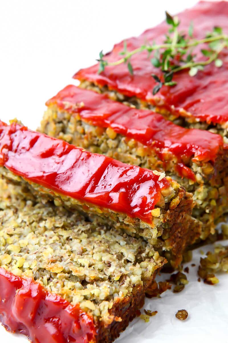 A gluten-free vegan lentil loaf with ketchup on the top, cut into slices.