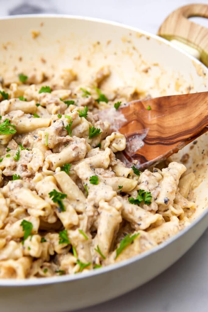 A white wok filled with vegan stroganoff sprinkled with fresh parsley.