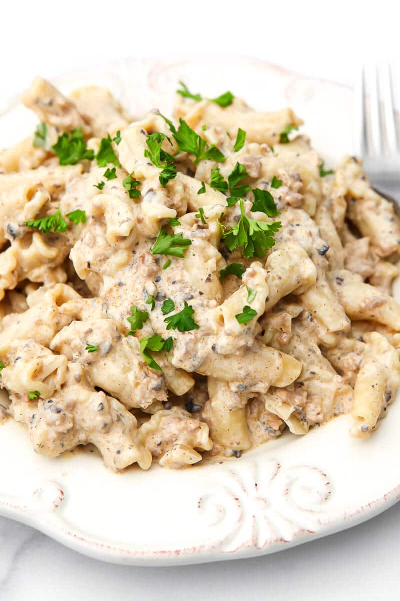 A white plate filled with creamy vegan beef stroganoff with parsley on top.