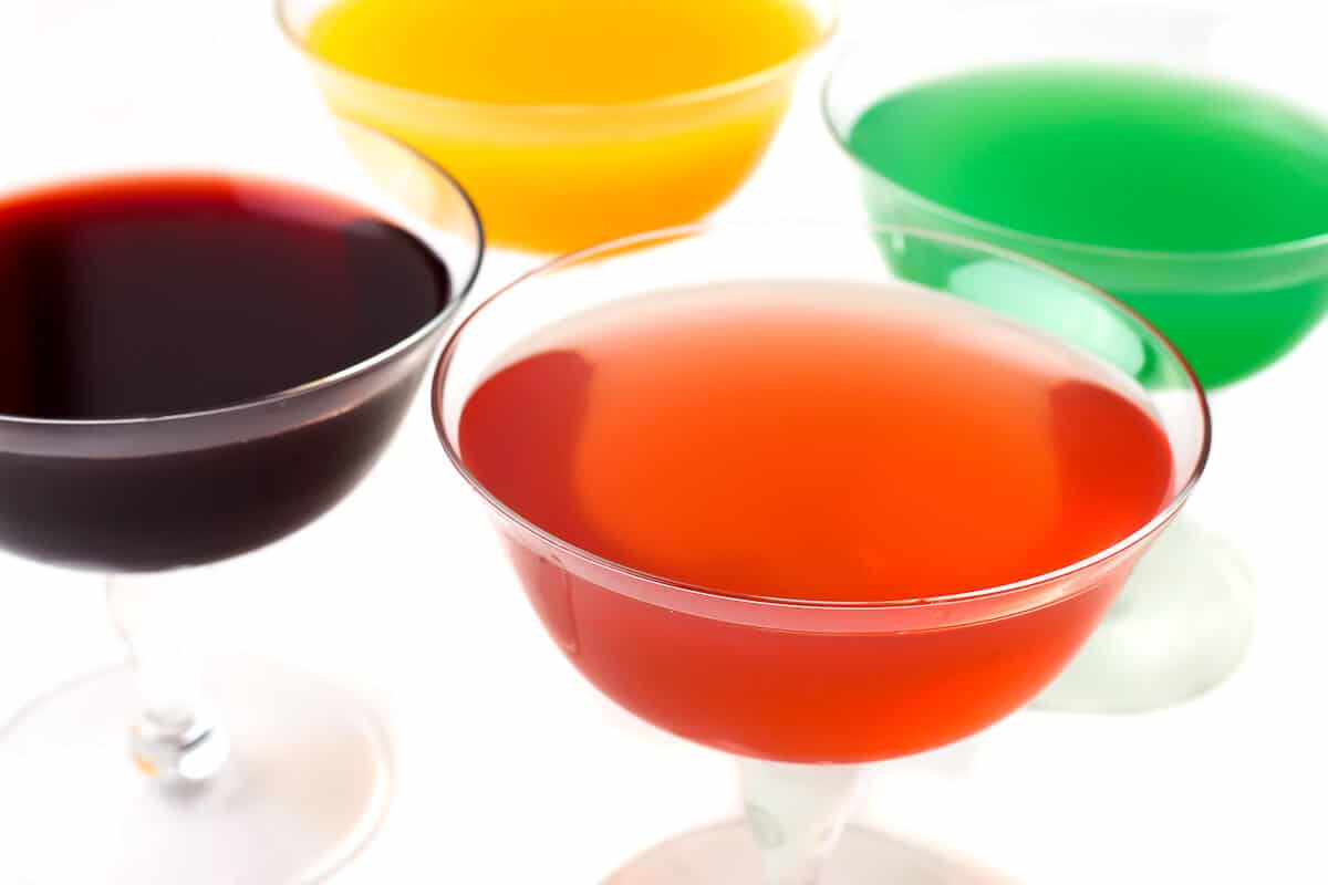 Four stemmed glasses filled with different flavors of vegan jello made with agar agar.