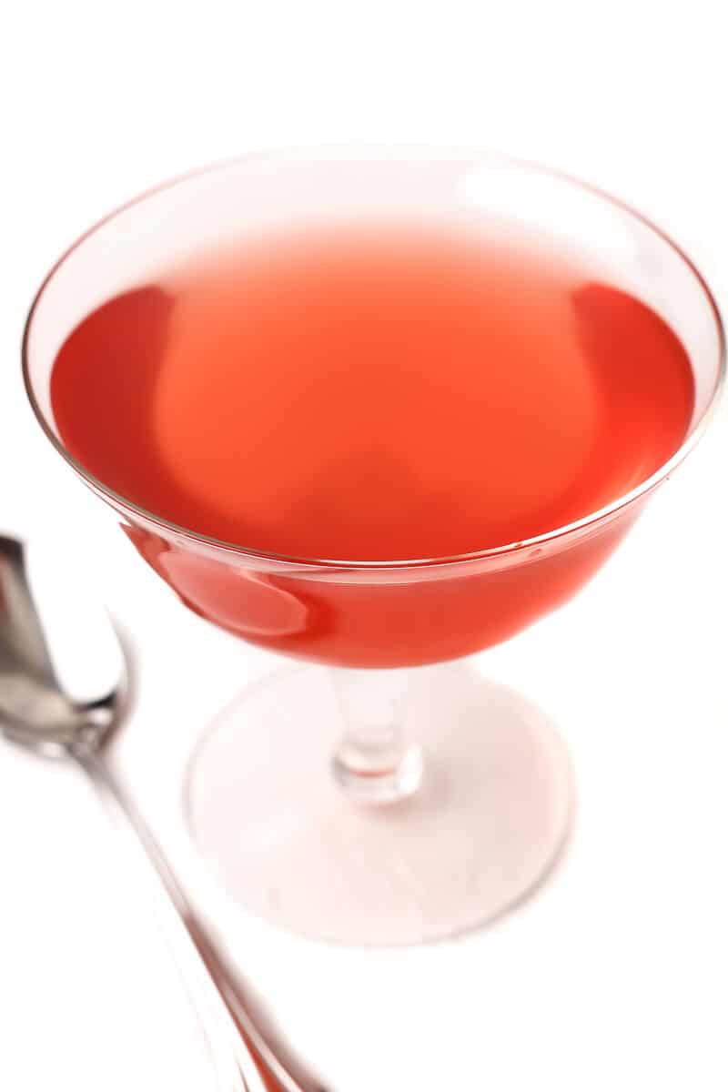 A stemmed glass with red vegan jello made with fruit juice.