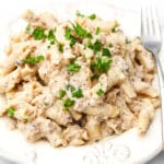 A white plate filled with vegan beef stroganoff with a fork on the side.