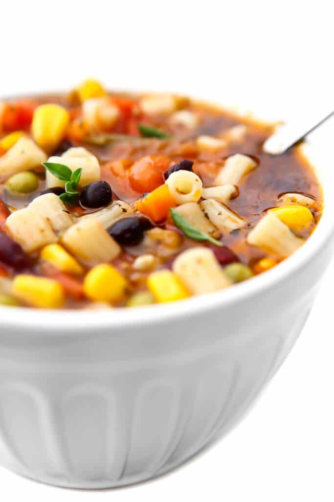 A white bowl filled with veggie packed minestrone soup. 