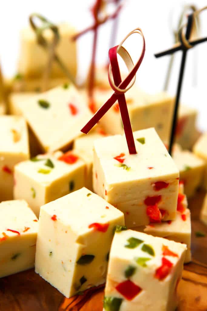 Vegan pepper jack cheese cubes on a cutting board.