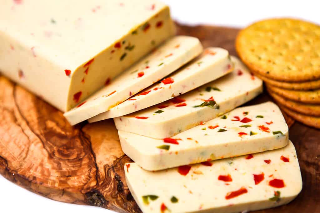 Dairy-free pepper jack cut into slices on a cutting board with crackers.