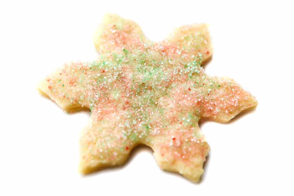 A vegan shortbread cookies cut out into a snowflake shape.