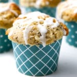 A close up of a vegan lemon poppy seed muffin with lemon drizzle on top in a blue muffin liner.