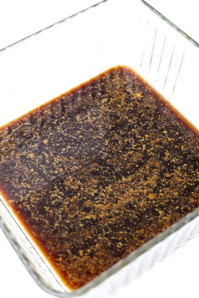 A low shallow dish filled with bacon flavored marinade to marinate the tempeh to make tempeh bacon.