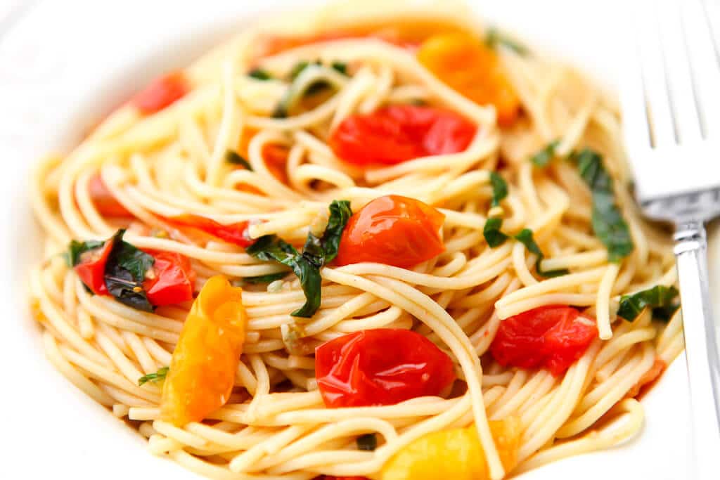 A bowl of pasta made with cherry tomatoes. 