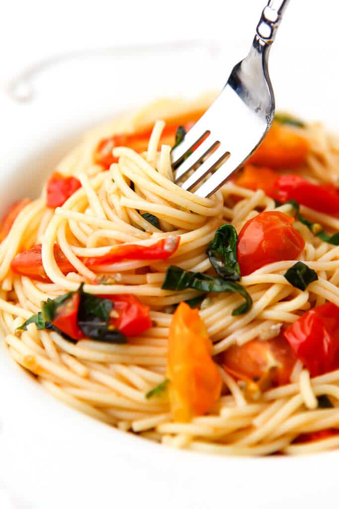 A plate of pasta with fresh tomato basil pasta sauce with a fork in it.