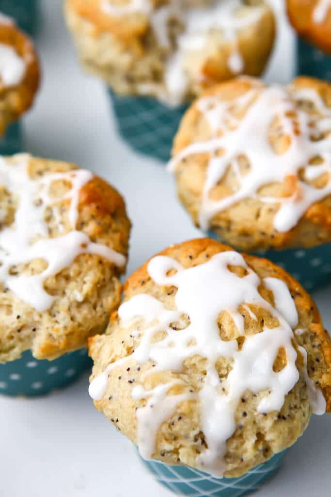 The tops of vegan lemon poppy seed muffins with lemon glaze drizzled on top of them.