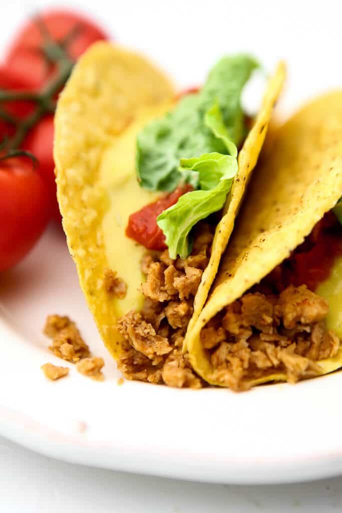 Two tacos on a white plate filled with homemade vegan taco meat.