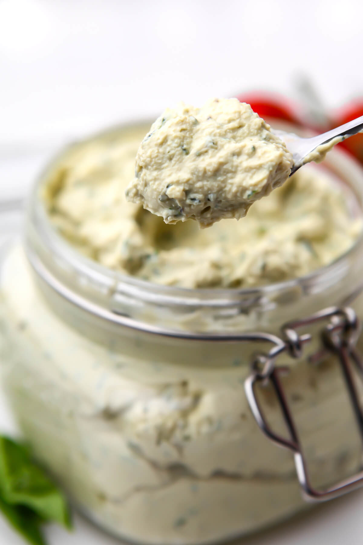 A glass jar full of tofu ricotta being scooped out with a spoon.