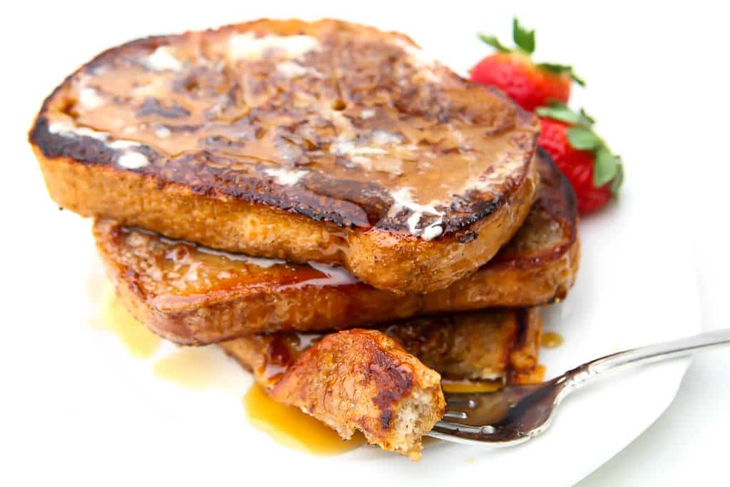 A stack of French toast with a fork full of toast on the side.