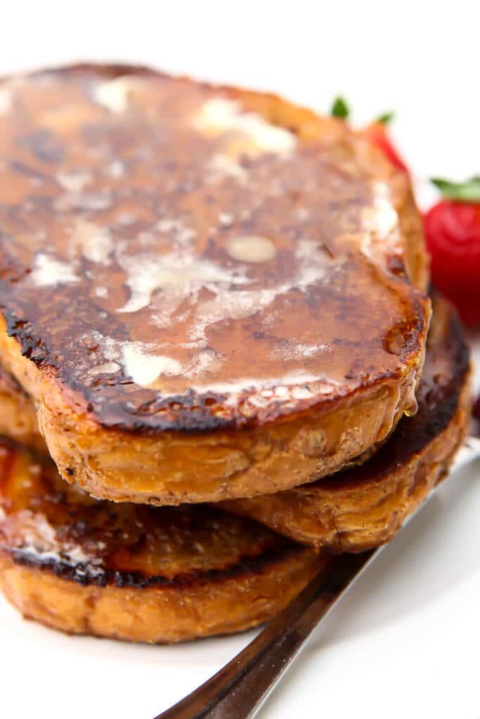 A stack of vegan French toast topped with butter and syrup.