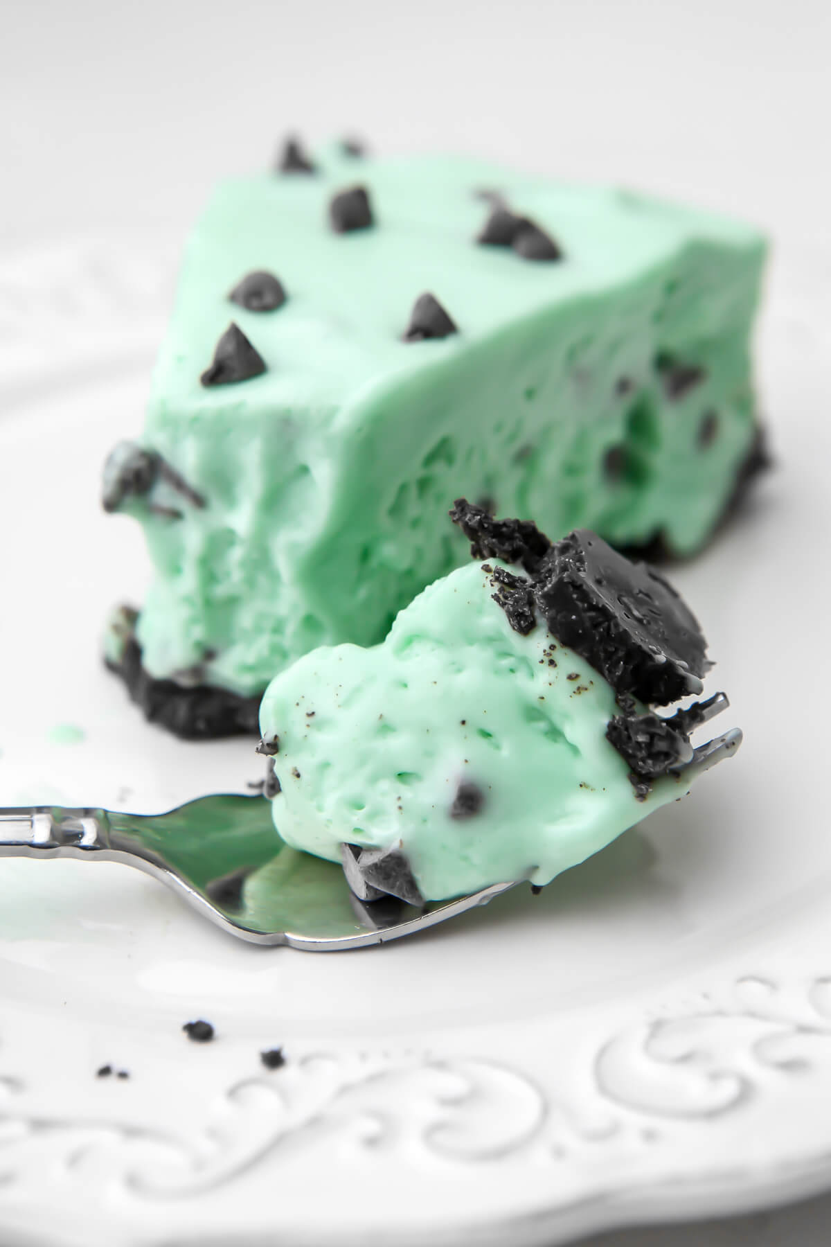 A slice of light green mint, vegan grasshopper pie with some on a fork next to the slice.