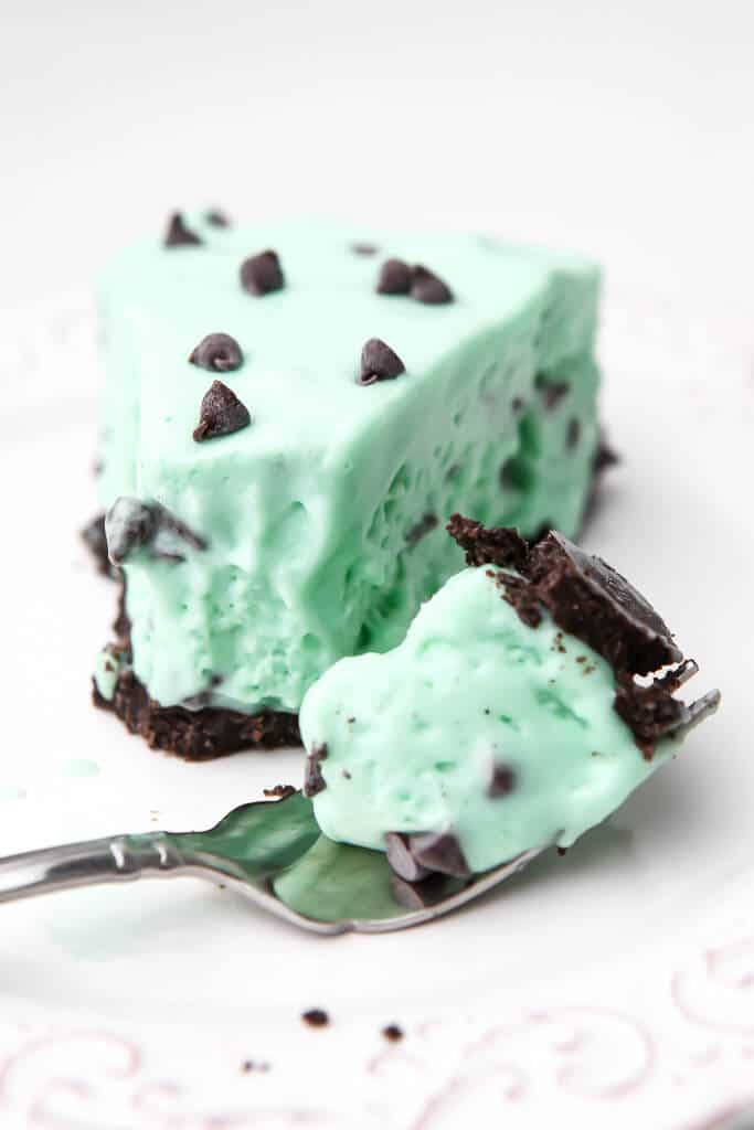 A slice of light green mint, vegan grasshopper pie with some on a fork next to the slice.