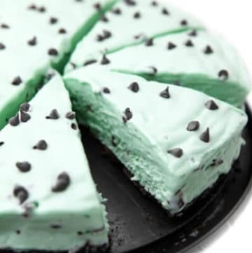 A vegan grasshopper pie with chocolate chips on it sliced into pieces.