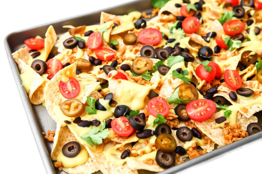 A tray of vegan sheet pan nachos loaded with vegan toppings.