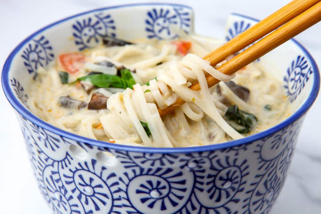 A bowl of vegan Thai soup with veggies and rice noodles.