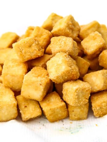 Crispy deep fried tofu cubes on a paper towel.