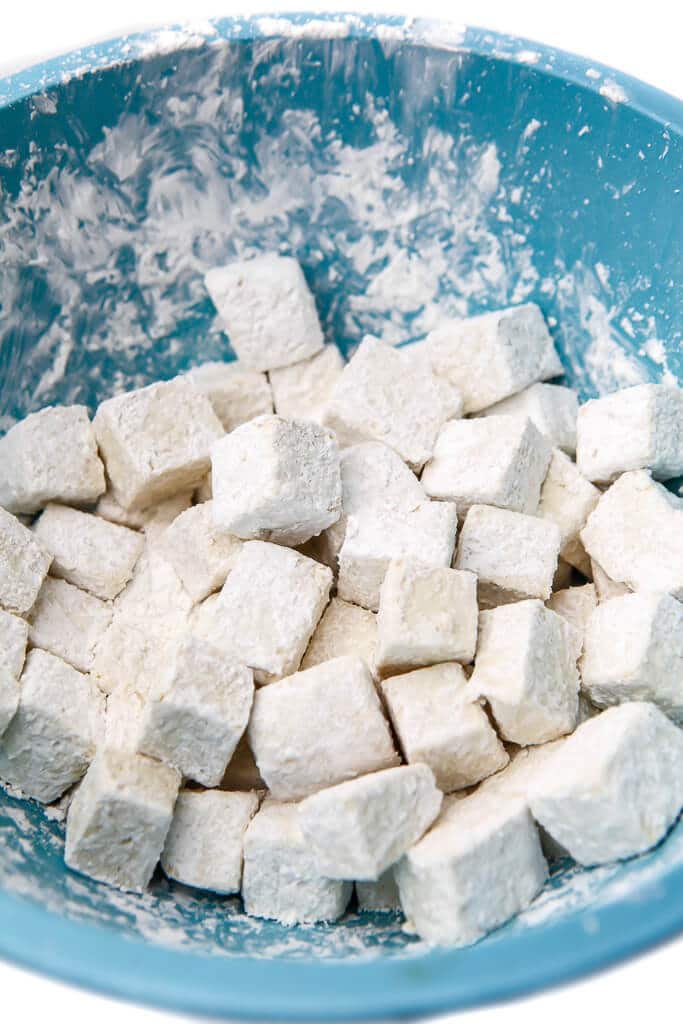 Cubes of tofu tossed cornstarch in a blue bowl.