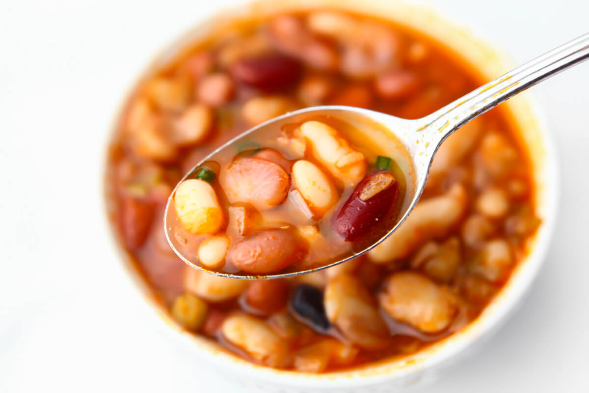 A bowl of 15 bean soup with a spoonful of it being held above the bowl.