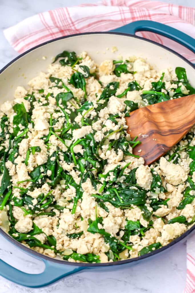 Tofu and spinach cooked down in a pan to use as the filling for spanakopita.