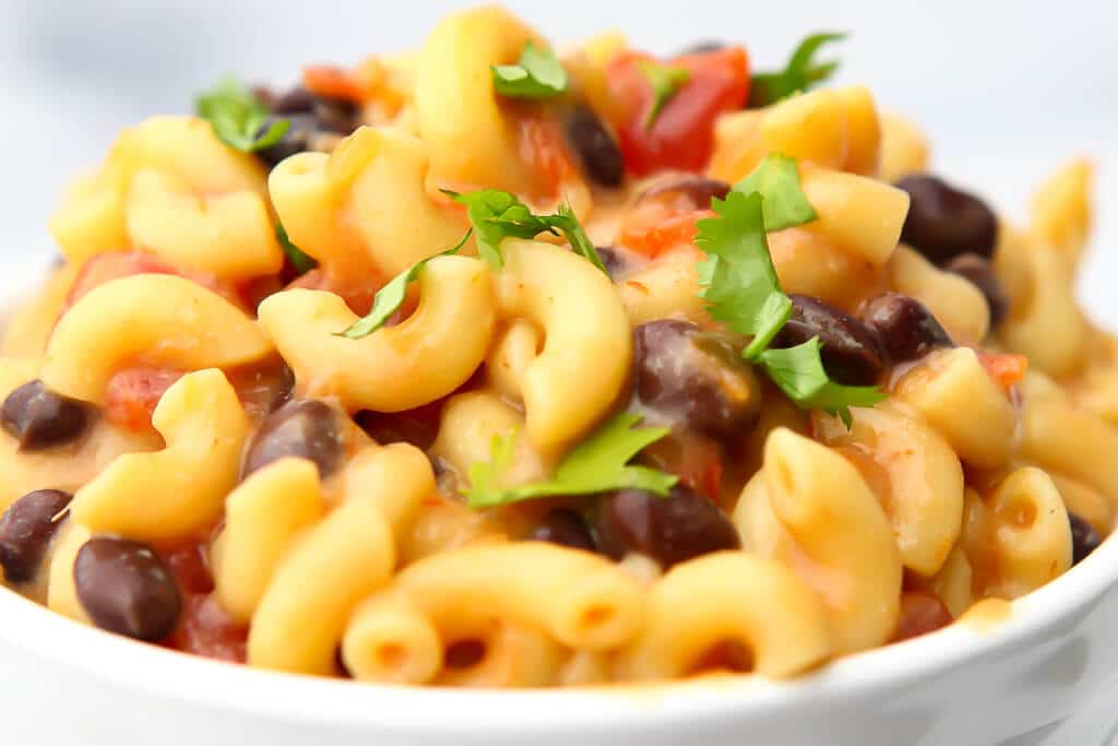 A close up of mac and cheese with beans, salsa, and cilantro.