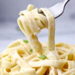 A close up of vegan Alfredo sauce made with coconut milk on a fork.