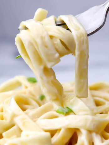 A close up of vegan Alfredo sauce made with coconut milk on a fork.