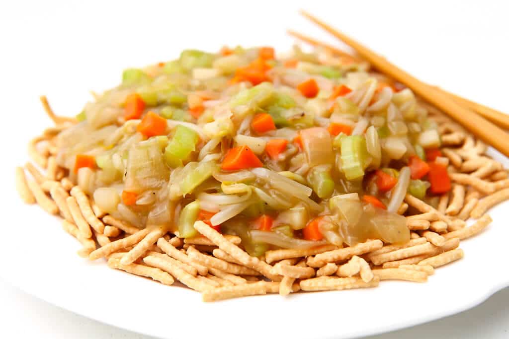 A plate full of vegan chop suey served over chow mein noodles.