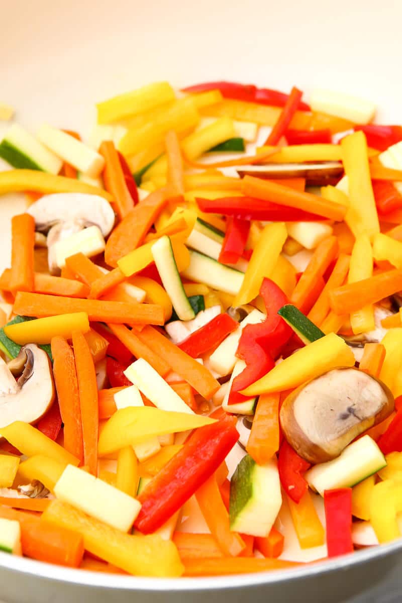 Carrots, bell peppers and mushrooms cut up small in a wok.