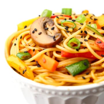 A bowl full of noodles and stir fried vegetables covered in teriyaki sauce.