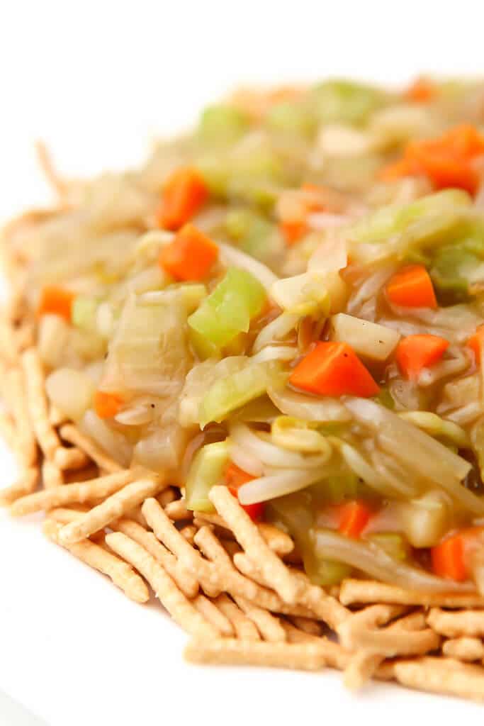 A close up of vegan chop suey served over crunchy chow mein noodles.
