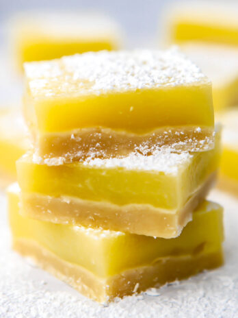 A stack of 3 vegan lemon bars dusted in powdered sugar.