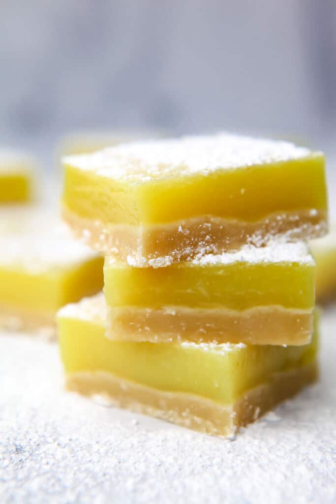 Three vegan lemon bars stacked on top of each other. 