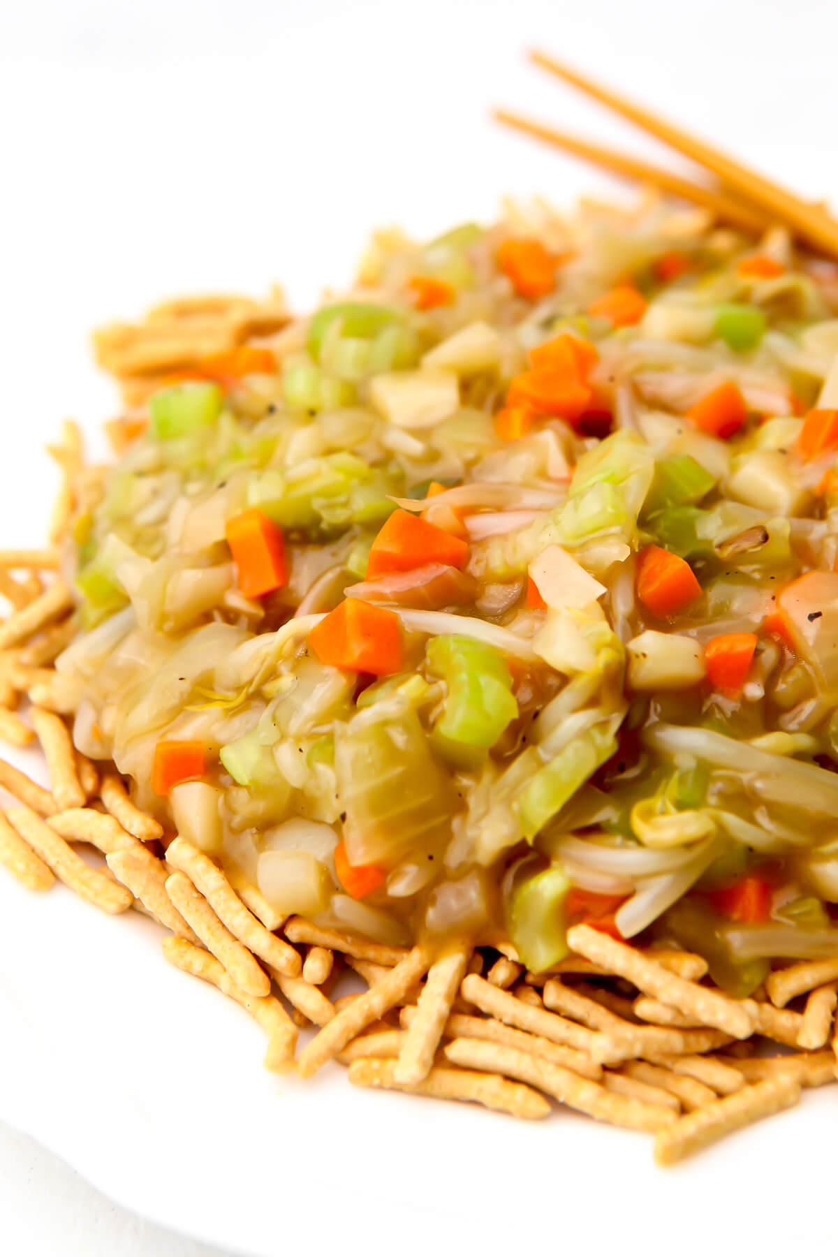 A white plate filled with chow mien noodles topped with vegetable chop suey.